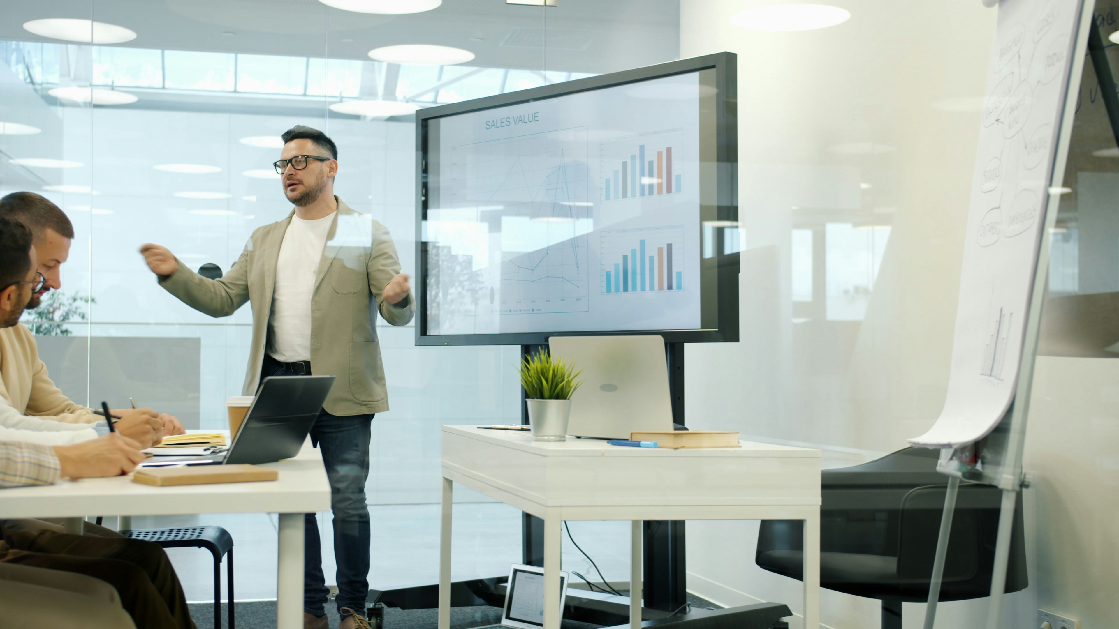A consultant presenting performance data to two colleagues in a meeting room
